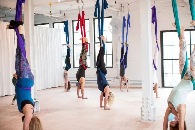 People doing handstand in aerial yoga class. 