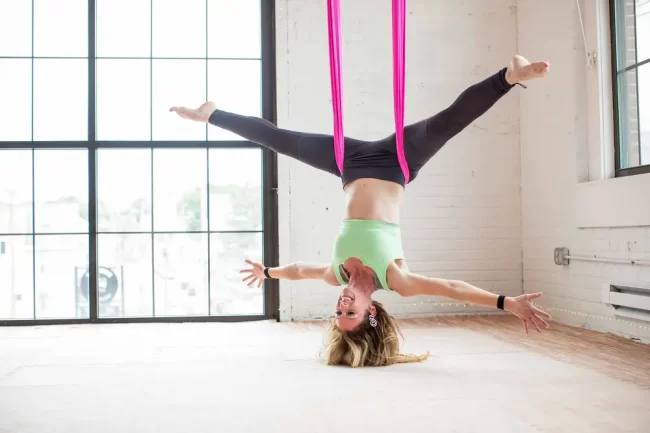 Woman smiling doing aerial yoga star pose.