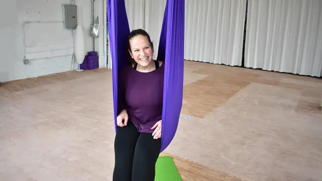 Aerial Yoga student relaxes after class supported by their aerial silk.