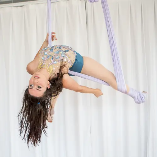 Aerial yoga student balances through a complex silks pose during her advanced level aerial yoga class at Earth & Aerial Yoga in Hudson MA.