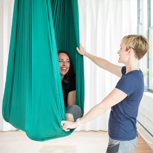 Teacher and co-founder Katherine Scalora guiding student and teacher Kara Herbertz during one of Earth and Aerial Yoga's 2023 Teacher Training Courses located in Hudson MA.