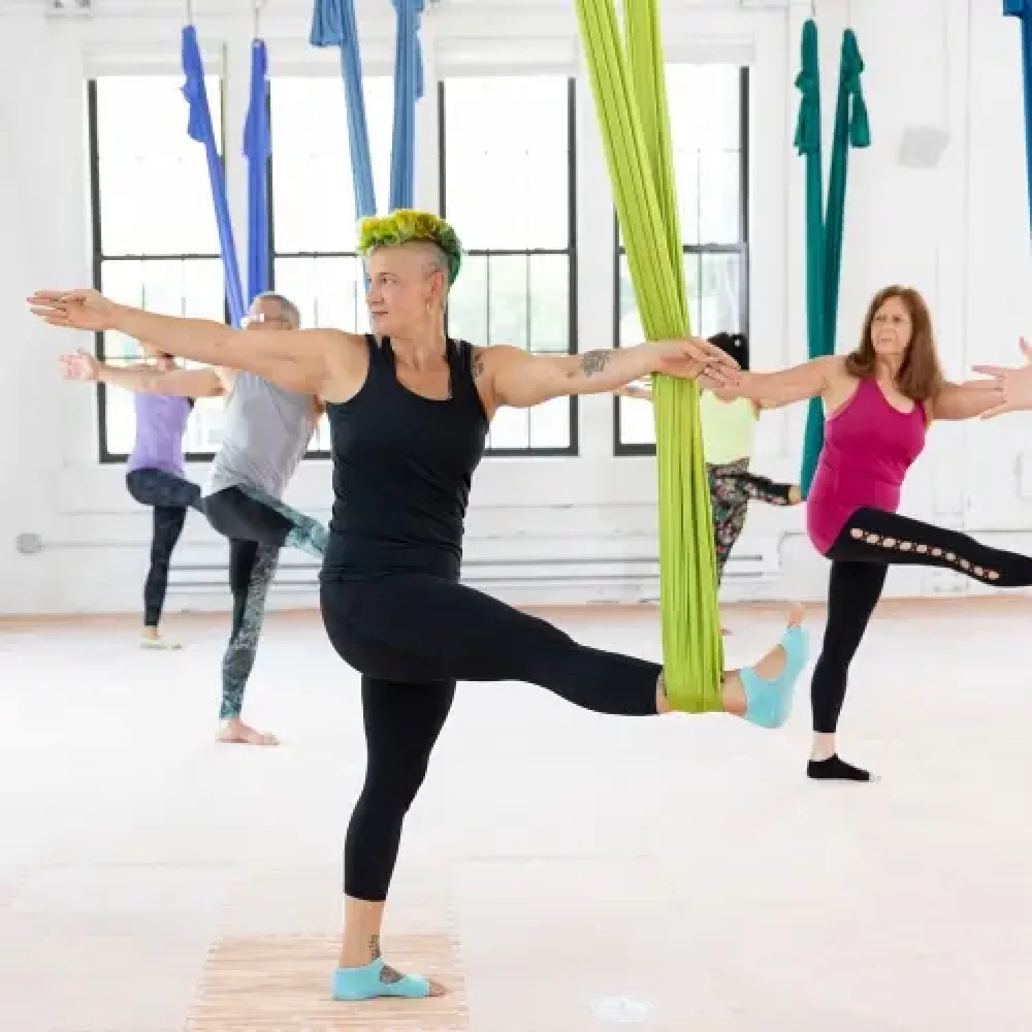 Aerial yoga students practice an aerial twist during their morning class provided by Earth an Aerial Yoga in Hudson MA.