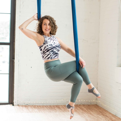 Woman sitting in aerial yoga silk.