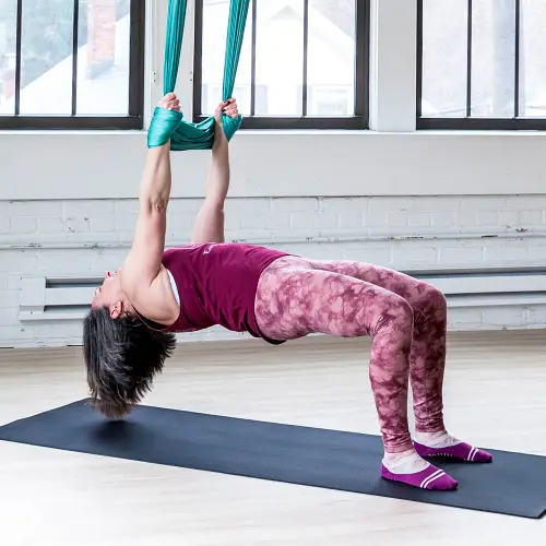 Woman doing a reverse table pull-up on aerial yoga silk